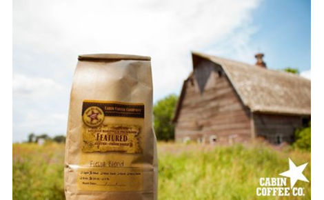 Background: old barn in a field. Foreground 1 pound bag of fresh roasted coffee