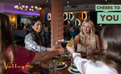 group of women at ZuZu doing a cheers; text says "Cheers to You"