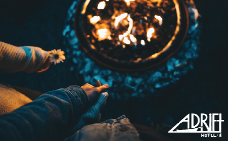 eGift card image of a couple holding hands by a fire with the Adrift Hospitality logo
